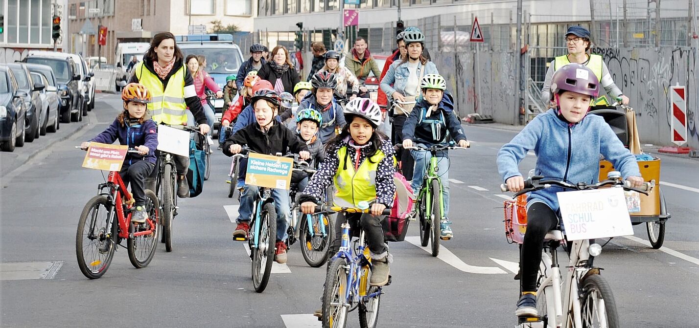 Beim Fahrradbus fahren Kinder und Eltern in der Gruppe auf der Straße.