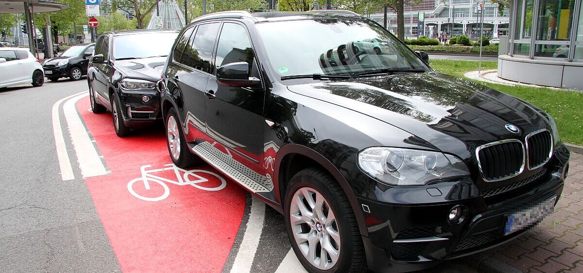 SUV parkt auf Radfahrstreifen Schwarzer SUV parkt auf rot markiertem Radfahrstreifen